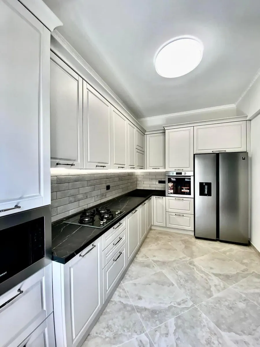 Cuisine blanche avec plan de travail marbré noir et électroménager inox